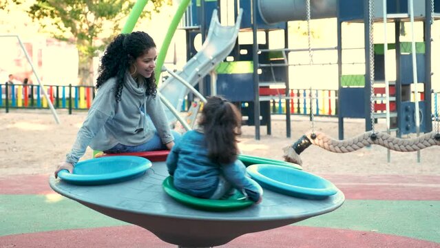 Latin family with two children playing together in a playground. Hispanic family.