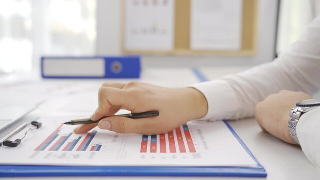 Successful businessman working, drawing graphs, taking notes.