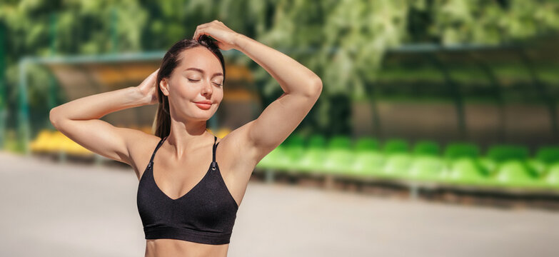 young woman doing a stretching her arms before a workout or training outdoor