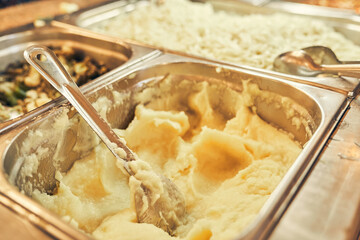 A self-service restaurant where the dishes are served by the customer himself. Close-up of whipped mashed potatoes in a metal tray with space for copying. High quality photo