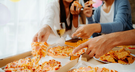 Group of young asian office girl friends having fun and celebrating pizza on table during party