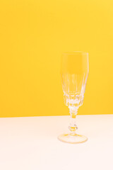 Empty crystal glass in front of yellow background. Place for your design.