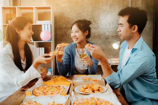 Office Pizza Party:  A group of young professionals gather around a table, enjoying pizza and drinks, sharing laughter and camaraderie.  The warm.