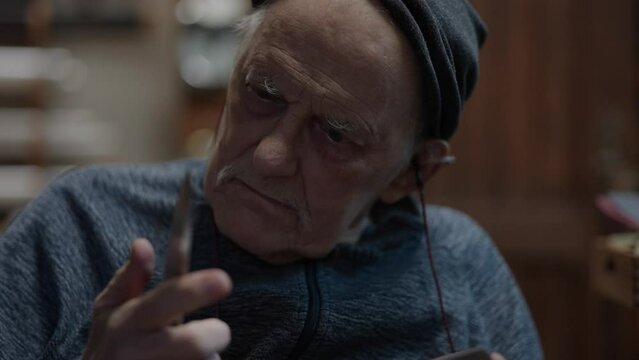 Senior gray haired male master in a wheelchair working at his workshop sharpening japanese deba knife