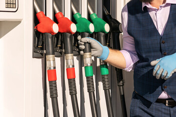 A man gasses his car at a gas station. close-up petrol pistols. concept of fuel shortage, economy,...