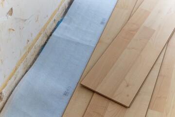 A close up portrait of a stacked pile of wood imitation laminate floorboards lying on some sound...