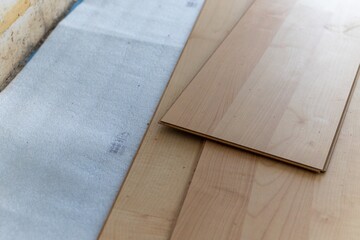 A close up portrait of stacked wood imitation laminate floorboards lying on some sound isolation...