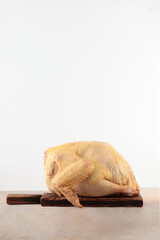 Duck fresh on wooden board. Preparing duck for holiday. Fresh whole duck. Thanksgiving day. Copy space. Isolated object. Side view.Vertical photo.