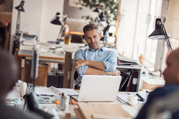 Fototapeta premium Middle aged Caucasian architect working on building plans in a modern company office