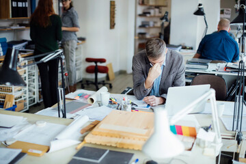 Tired overworked architect sitting in a modern office