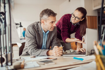 Young man and woman using the laptop while working together on a project in a startup company office