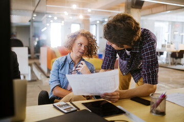 Young group of coworkers going over paperwork in the office of a startup company