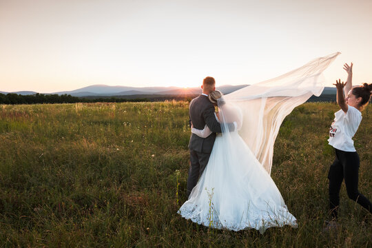 a young couple in love looks at the future together, a photo full of love and tenderness, women holding the bride, the bride and groom in the middle of beautiful nature, sunset before them