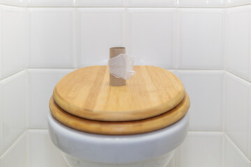 body, bathroom and personal hygiene, a closed wooden toilet lid with an empty roll of toilet paper