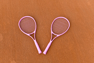 Pink tennis rackets on clay coart, concept for breast cancer awareness month 
