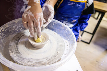 The teacher teaches the children to sculpt from clay on a potter's wheel. Pottery lesson