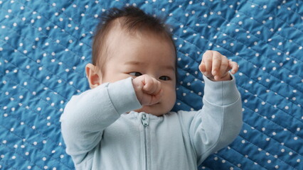 Three months old baby boy discovering his hands for the first time and staring at them curiously.