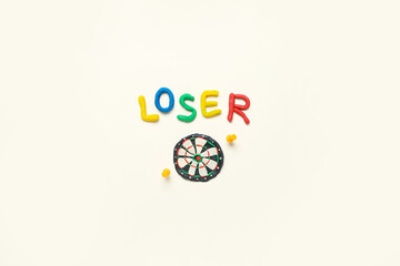 Word LOSER with dartboard made of plasticine and pins on white background