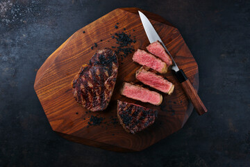 Barbecue dry aged angus roast beef steak sliced and as piece with black salt served as top view on...