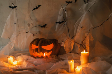 Happy Halloween! Spooky Jack o lantern carved pumpkin, spider web, ghost, bats and glowing light in...