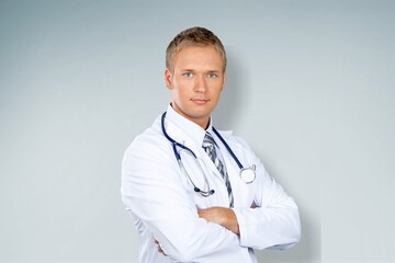 Professional doctor in medical coat over light wall background