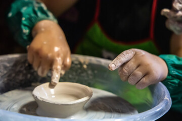 child tries their hand at shaping a ceramic plate on the potter's wheel.