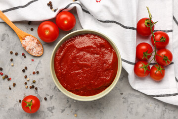 Bowl with tasty tomato paste and fresh vegetables on grunge background