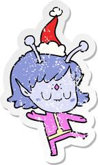 hand drawn distressed sticker cartoon of a alien girl wearing santa hat