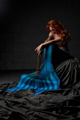Lonely mermaid sitting on the rock with her head down