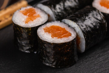 Maki sushi roll with salmon avocado and tobiko caviar served on black board close-up - Japanese food