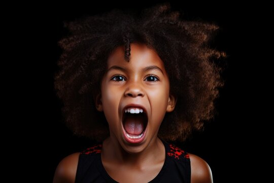 A young girl with her mouth wide open against a black background. This image can be used to depict surprise, shock, or astonishment in various contexts.