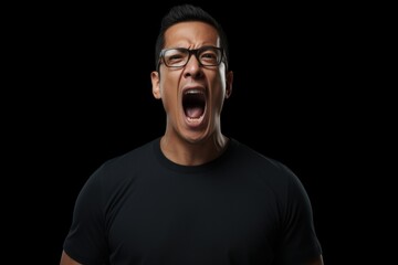 A man wearing glasses and a black shirt is captured in the midst of a loud scream. This intense expression of emotion can be used to depict frustration, anger, or fear in various creative projects.