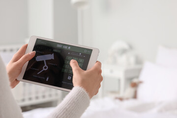 Woman using smart home security system control panel in bedroom, closeup