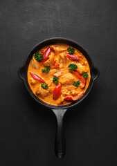 Chicken paprikash dish with paprika, onion, sweet pepper in black pan on dark table. top view - obrazy, fototapety, plakaty