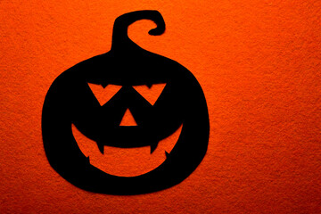 Black paper pumpkin on orange background