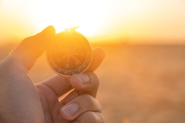 hand holds a compass in the dawn light. Search concept. Sunset background