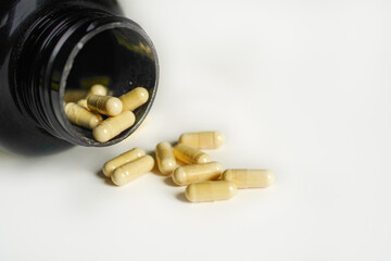 Vitamin D capsules on a green leaf with white background.