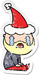 hand drawn distressed sticker cartoon of a bearded man crying wearing santa hat