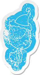 quirky cartoon distressed sticker of a squinting girl in dress wearing santa hat