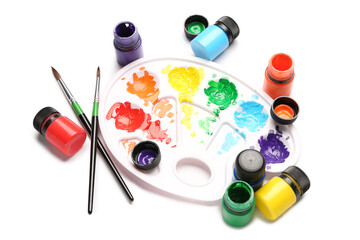 Jars of colorful gouache paints with artist's palette and brushes on white background