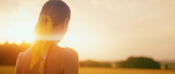 Girl watching the sunset on field on a warm summer evening.