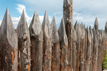 Fence made of chiseled stakes logs antique fencing close-up