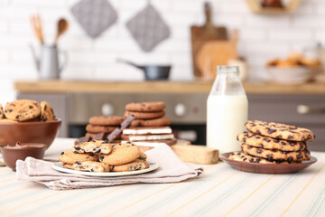 Cookies with chocolate and bottle of milk on table in kitchen