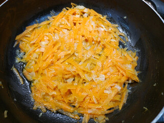 Fry onions and carrots in a frying pan with oil. Preparing to cook the main course. recipe. tasty and healthy food. ingredient for soups, stews and other dishes