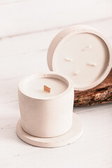 Holders with candles and tree bark on white wooden background