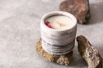 Holder with candle and stones on grey background