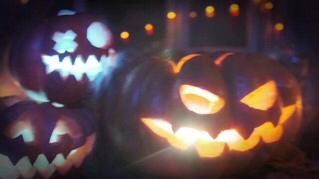 Three carved traditional flickering pumpkins at night, joyful and happy Jack-O-Lanterns greets people and his friends during Halloween celebration, creepy background.