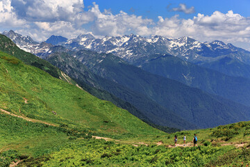 Large, high, green mountains, snow on the peaks, summer, sunny day, tourists walking along the path, Abkhazia, forest.