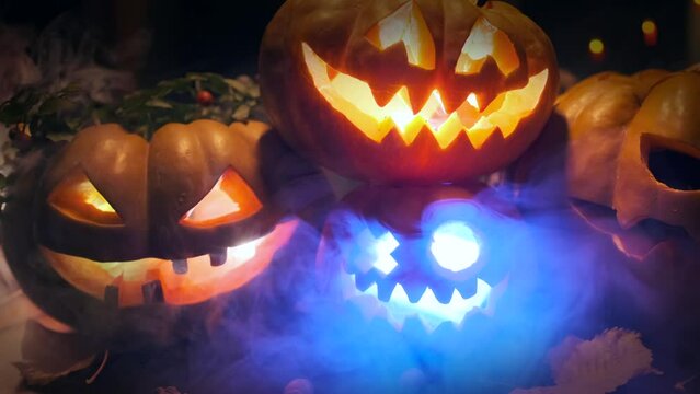 In foggy smoke Jack O Lanterns glowing light from within scary Halloween festive background party invitation autumn decoration on doorstep with flickering garlands, tracking shot.