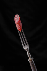 meat snacks on a fork, on a black isolated background